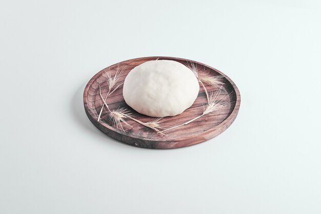Masa de bollo de pan redondo hecha a mano en una bandeja de madera en el medio.