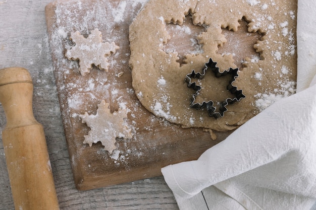 Masa cerca de cortador de galletas en tabla de cortar