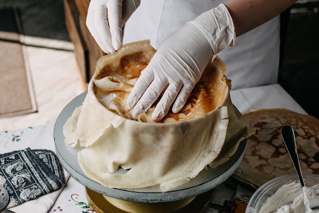 masa dentro de una sartén redonda con el cocinero esparciendo rodajas dentro de la cocina