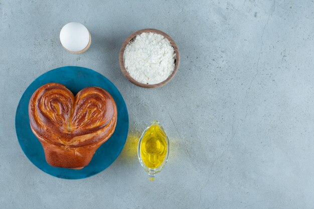 Masa dulce, harina y aceite de oliva sobre superficie de mármol.