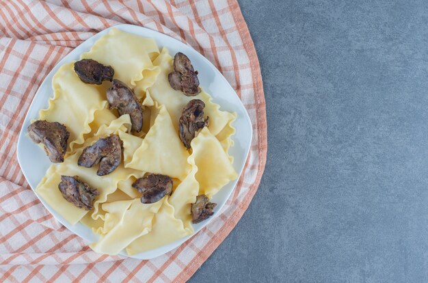 Masa hervida con partes de carne seca en un plato blanco.