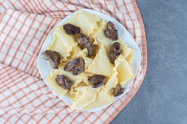 Masa hervida con partes de carne seca en un plato blanco.