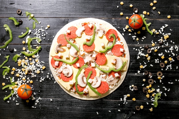 Masa de pizza con queso de champiñones pepperoni en la parte superior junto al queso espolvoreado tomate de maíz verde oliva