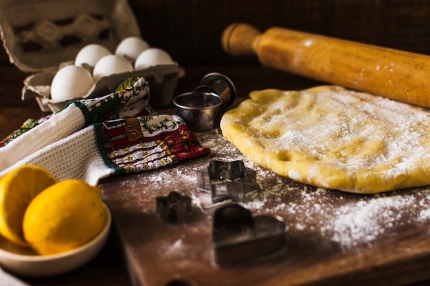 Masa y rodillo cerca de cortadores de galletas y toalla