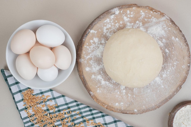 Masa con tres huevos blancos frescos de pollo sobre tabla de cortar de madera.