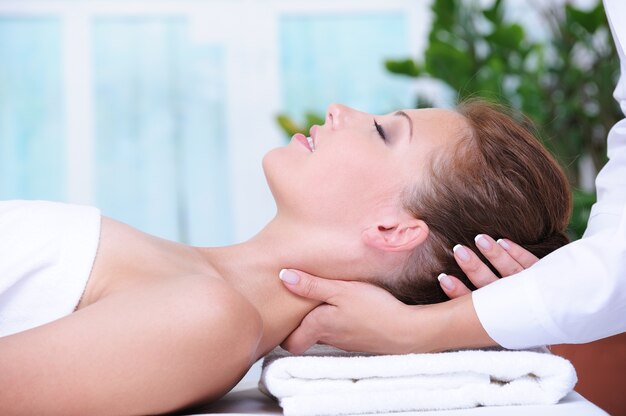 Masaje de cuello para mujer joven relajante en el salón de spa