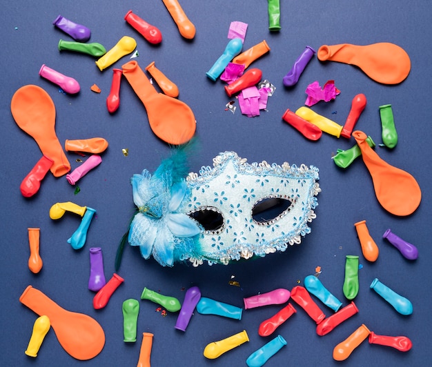 Máscara de carnaval azul y globos de colores y confeti.