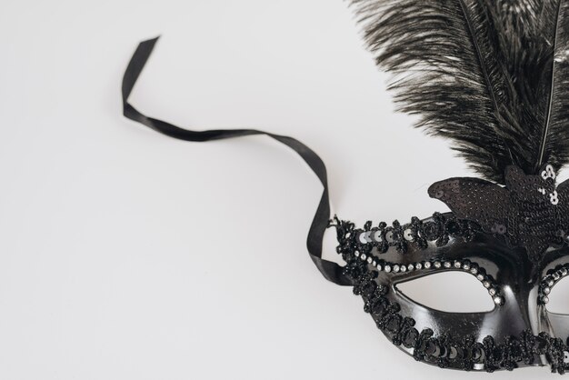 Máscara de carnaval negro con pluma en mesa