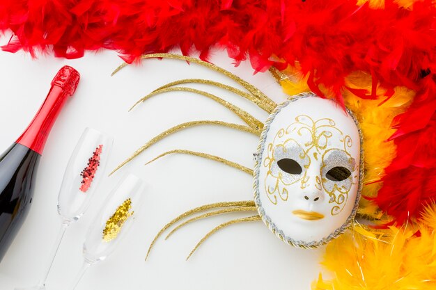 Máscara de carnaval con plumas y champaña.