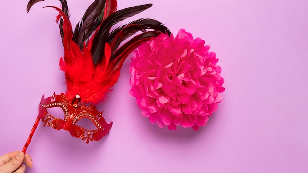 Máscara de carnaval rojo con plumas sobre fondo rosa