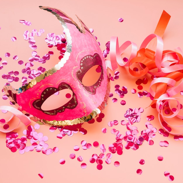 Máscara cerca de cintas y set de confeti rosa.