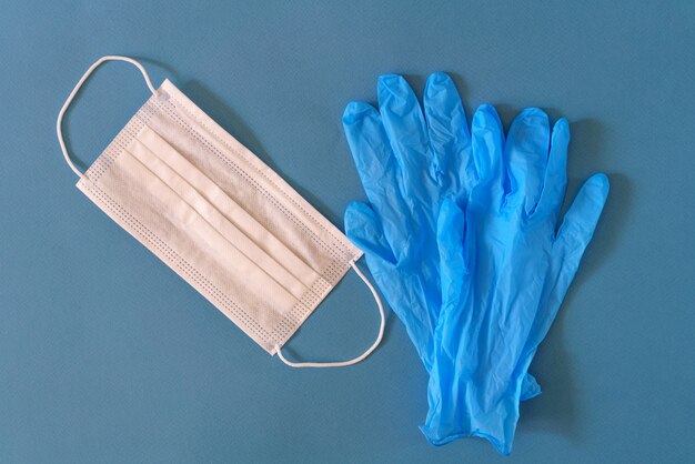 Máscara médica y guantes sobre una mesa azul