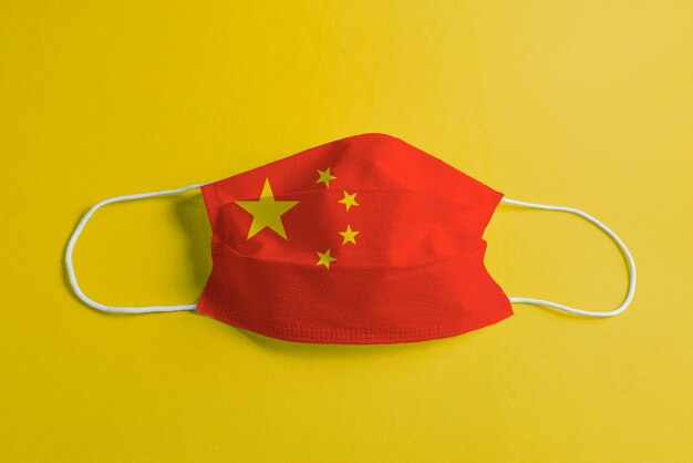 Máscara quirúrgica sobre fondo amarillo con bandera de China