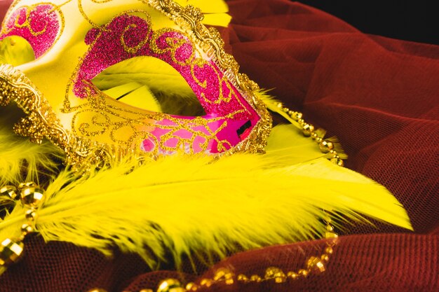 Máscara veneciana dorada con plumas sobre una tela roja