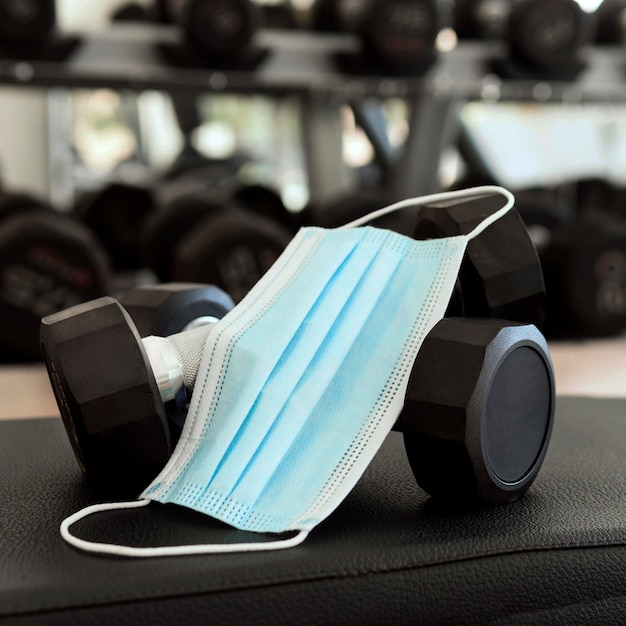 Foto gratuita mascarilla médica y pesas en el gimnasio.