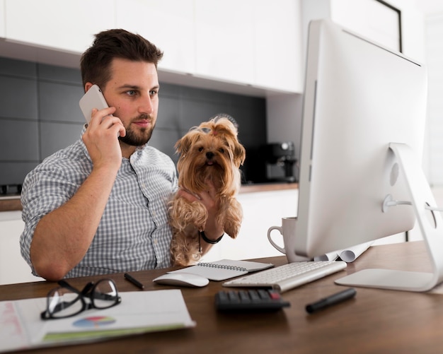 Masculino adulto casual sosteniendo mascota mientras trabaja