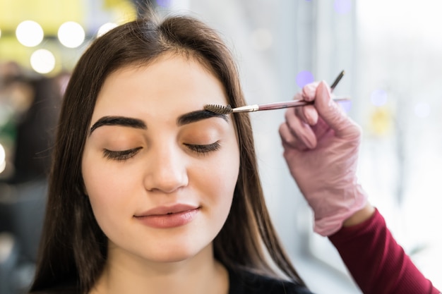 Master haciendo pasos finales en maquillaje para modelo con ojos cerrados