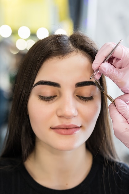 Foto gratuita master haciendo pasos finales en el procedimiento de maquillaje para modelo con ojos verdes