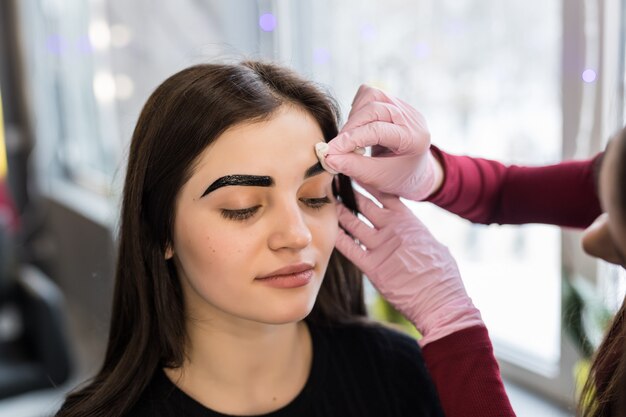 Master haciendo los pasos finales en el procedimiento de maquillaje en el salón