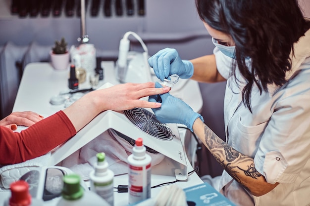 Master manicura cepillando las uñas del cliente después del proceso de manicura en el salón de belleza