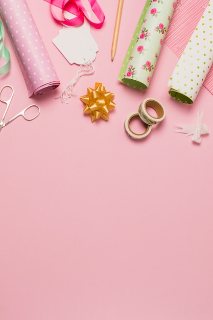 Foto gratuita material y accesorio para envolver regalo dispuesto sobre superficie rosa.