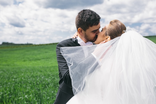 Matrimonio dándose un beso apasionado al aire libre