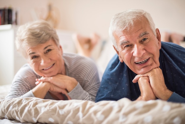 Matrimonio senior alegre descansando en el dormitorio