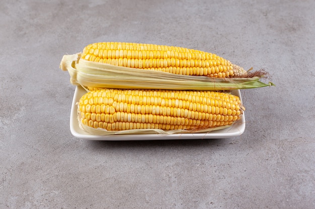 Mazorcas de maíz dulce fresco aislado en la placa blanca.