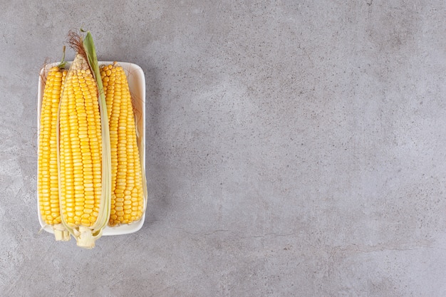 Foto gratuita mazorcas de maíz dulce fresco aislado en la placa blanca.