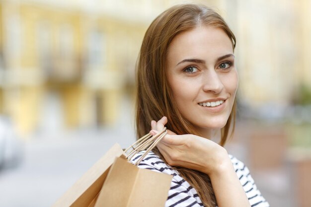 Me encanta ir de compras Primer plano de una hermosa mujer de cabello oscuro sonriendo a la cámara con sus compras en la mano