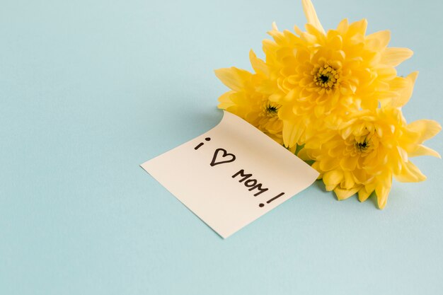 Me encanta mamá nota cerca de flores amarillas