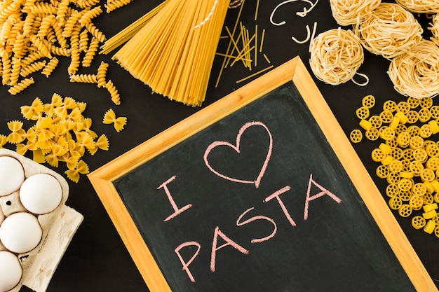 Foto gratuita me encanta el texto de pasta escrito en pizarra rodeado de pasta sin cocer.