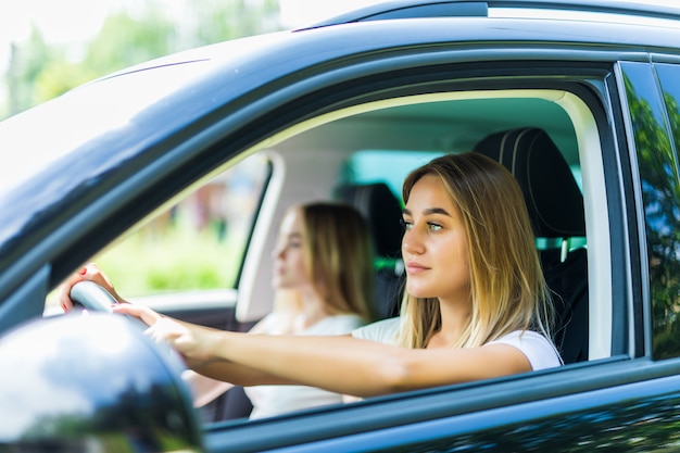 Me encanta este viaje por carretera. Dos hermosas mujeres alegres jóvenes con sonrisa mientras está sentado en el coche