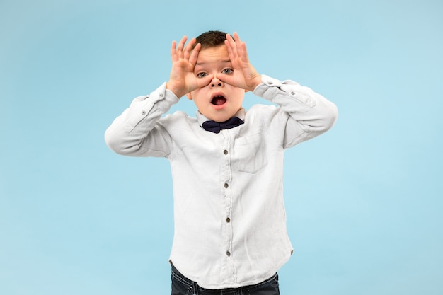 Foto gratuita me temo que. susto. retrato del niño asustado. adolescente de pie aislado en el fondo de estudio azul de moda. retrato masculino de medio cuerpo. las emociones humanas, el concepto de expresión facial.