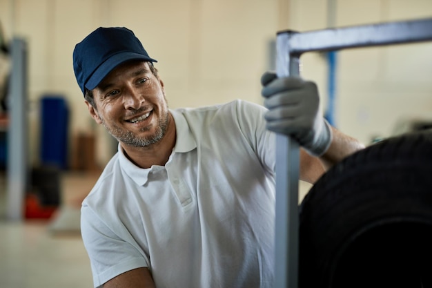 Foto gratuita mecánico adulto medio feliz que trabaja en taller de reparación de automóviles