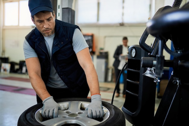 Foto gratuita mecánico adulto medio que trabaja con neumáticos de automóviles en un taller de reparación de automóviles