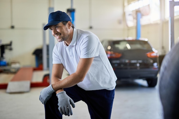 Mecánico de automóviles feliz descansando mientras trabaja en un taller de reparación de automóviles