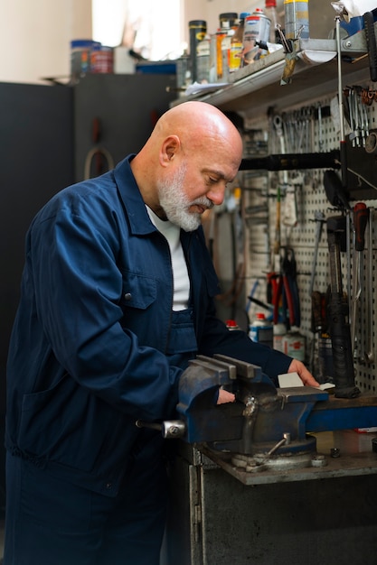 Foto gratuita mecánico de automóviles masculino que trabaja en el taller de reparación de automóviles