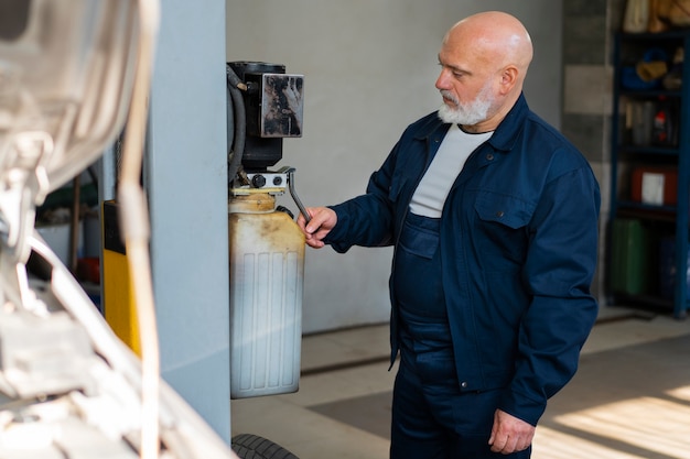 Mecánico de automóviles masculino que trabaja en el taller de reparación de automóviles