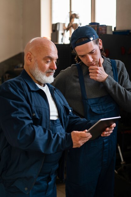 Mecánico de automóviles masculino usando un dispositivo de tableta en el taller de reparación de automóviles