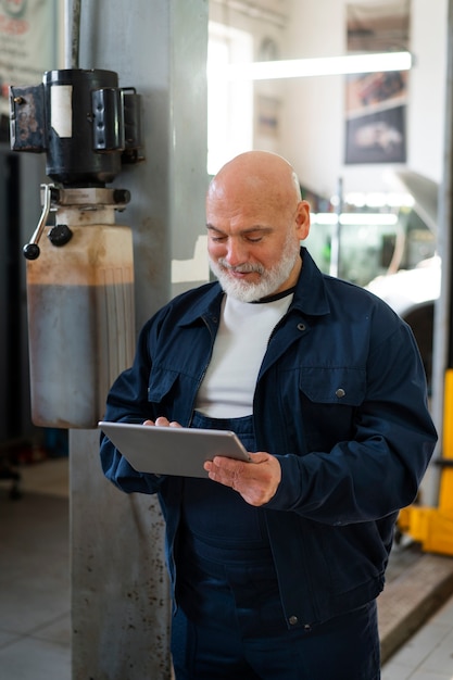 Mecánico de automóviles masculino usando un dispositivo de tableta en el taller de reparación de automóviles