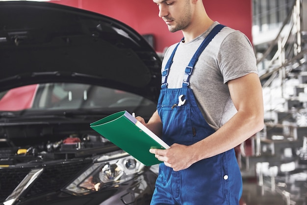 Foto gratuita mecánico de automóviles o herrero con portapapeles en el taller.