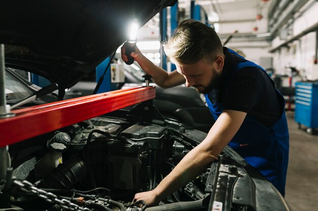 Mecánico de automóviles que mira la sala de máquinas del coche