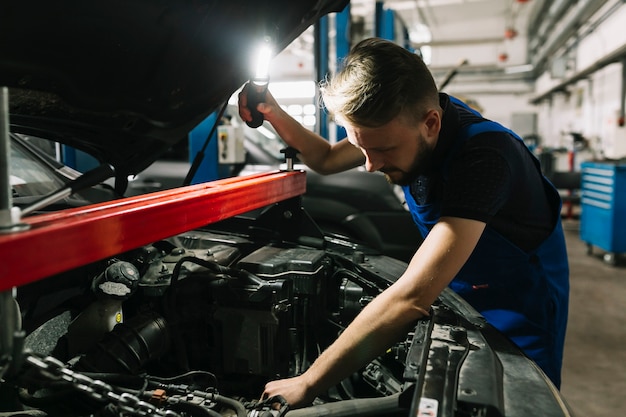 Mecánico de automóviles que mira la sala de máquinas del coche