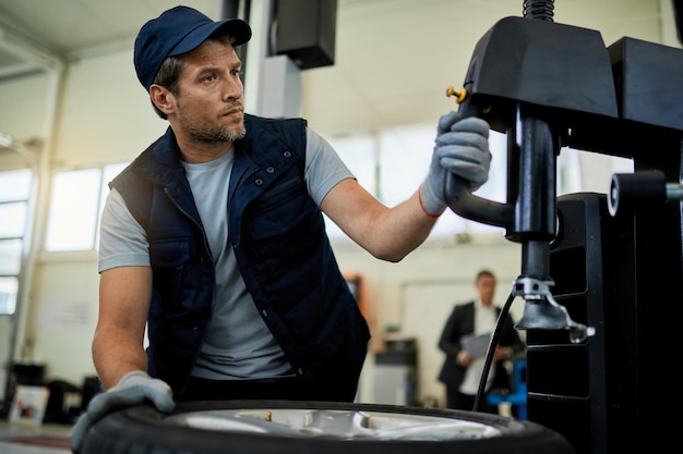 Mecánico de automóviles reparando neumáticos de automóviles mientras trabaja en un taller