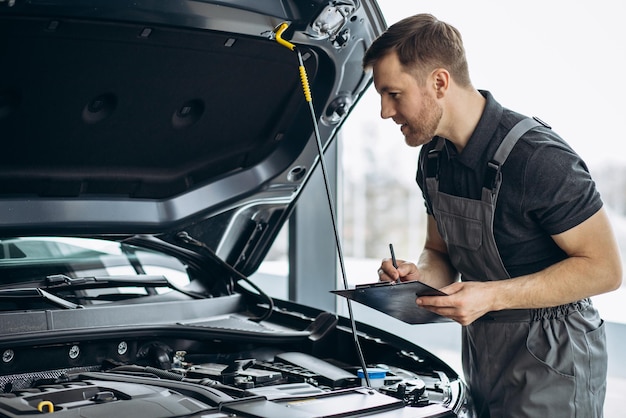 Foto gratuita mecánico de automóviles en el servicio de automóviles revisando el automóvil