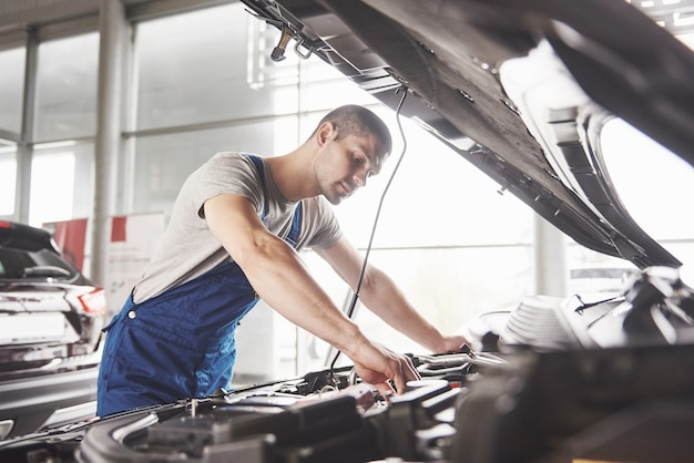 Mecánico de automóviles trabajando en garaje. Servicio de reparación.