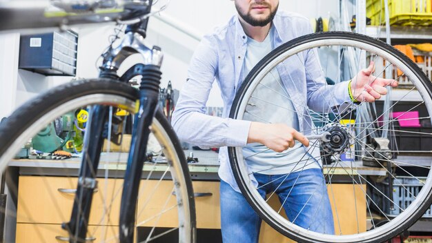 Mecánico de la bicicleta que repara el neumático de la bicicleta con la llave