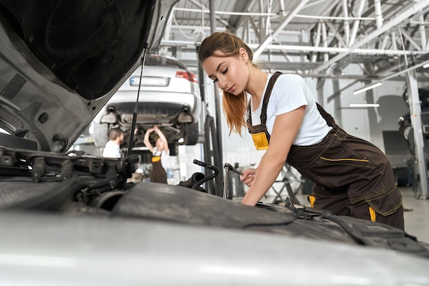 Mecánico en camisa blanca y overol motor de reparación