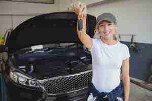 Foto gratuita mecánico femenino en garaje sosteniendo la llave del coche